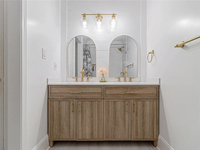 bathroom with a sink, baseboards, and double vanity