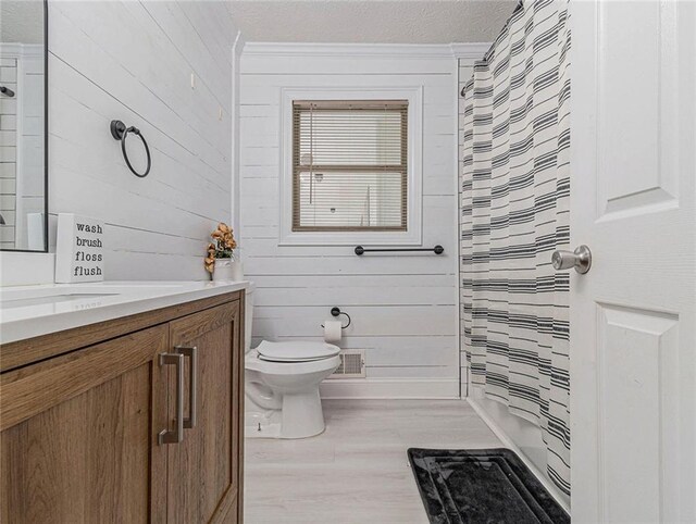 bathroom with vanity, toilet, curtained shower, wood finished floors, and visible vents