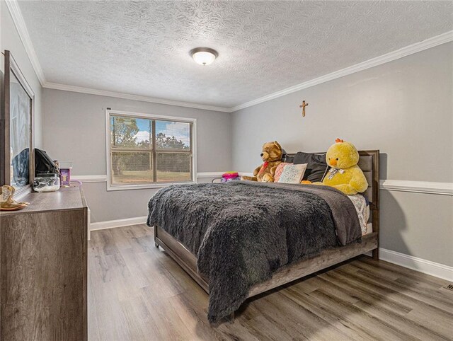 bedroom with crown molding, a textured ceiling, baseboards, and wood finished floors