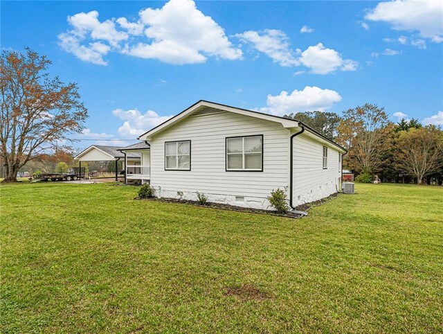 view of side of property with a lawn, crawl space, and central AC