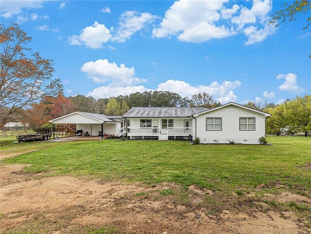 rear view of house with covered porch, an attached carport, dirt driveway, crawl space, and a yard