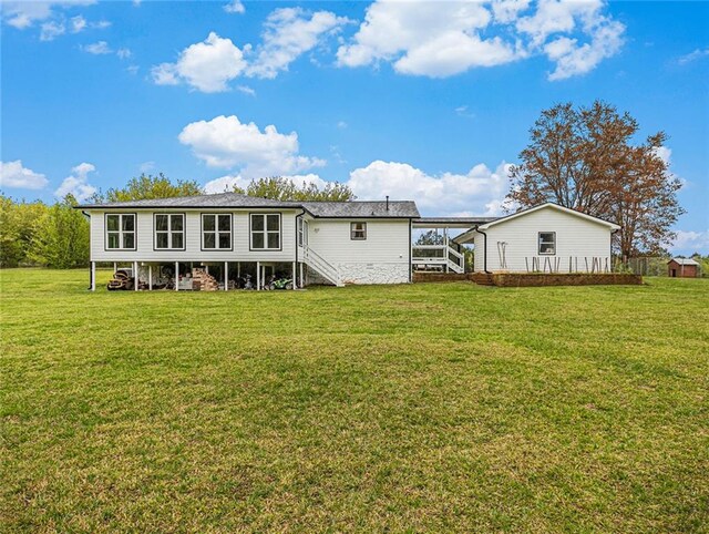 rear view of property with stairs and a yard