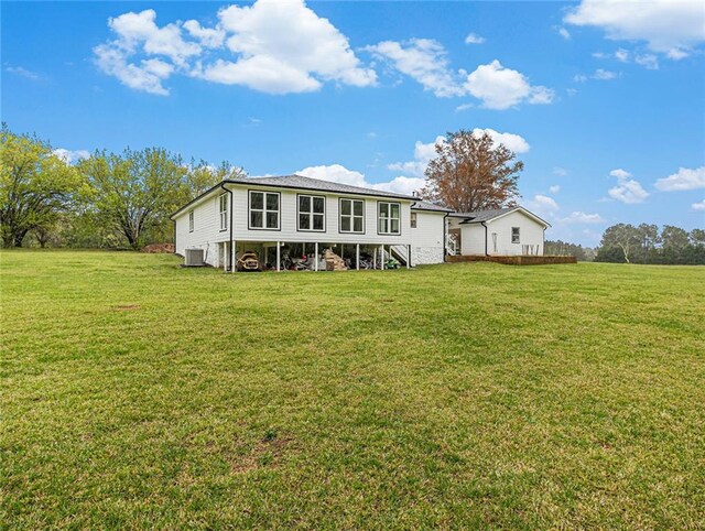 rear view of house featuring a lawn and cooling unit