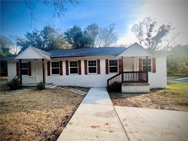 ranch-style home featuring covered porch and brick siding