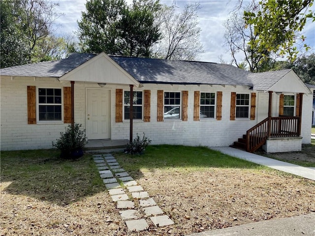 single story home with roof with shingles, brick siding, and a front lawn