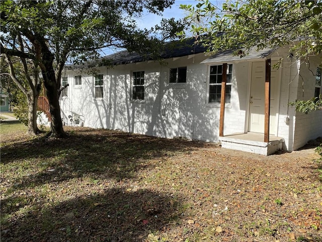 back of house featuring concrete block siding and roof with shingles