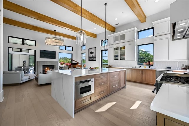 8200 Main St S Unit 1306, Woodstock, GA 30188 - kitchen with beam ceiling, light wood-style floors, a center island, glass insert cabinets, and hanging light fixtures