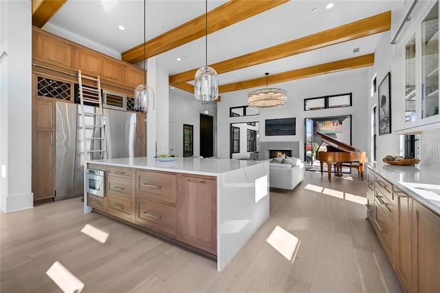 8200 Main St S Unit 1306, Woodstock, GA 30188 - kitchen featuring beam ceiling, a lit fireplace, light wood finished floors, glass insert cabinets, and light countertops