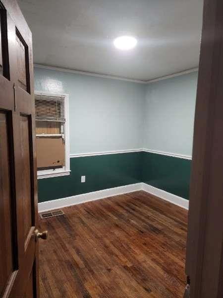 empty room featuring dark wood-type flooring and ornamental molding