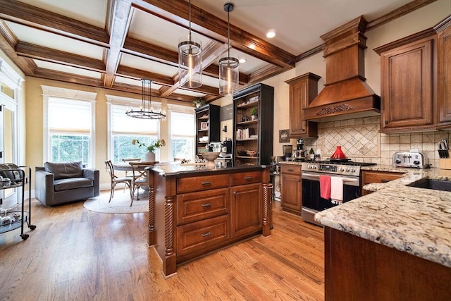 kitchen with pendant lighting, stainless steel range oven, light wood-type flooring, and custom exhaust hood