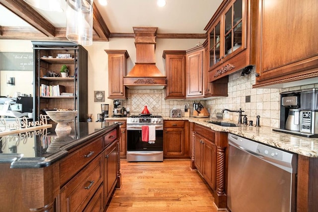 kitchen featuring premium range hood, light hardwood / wood-style floors, light stone countertops, appliances with stainless steel finishes, and sink