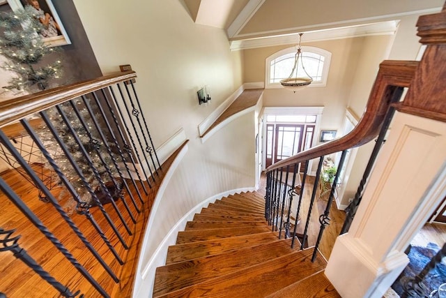 staircase featuring crown molding, dark wood-type flooring, and a towering ceiling