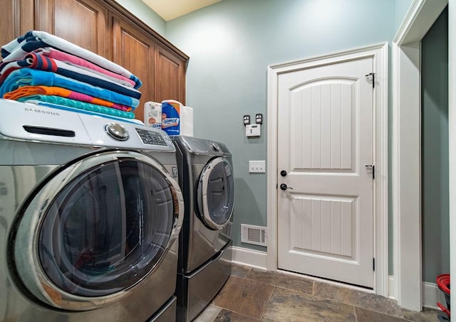 washroom featuring dark tile flooring, cabinets, and washer and dryer