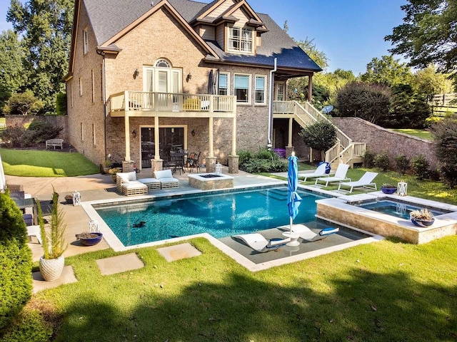 rear view of house featuring a balcony, a lawn, a patio area, and a pool with hot tub