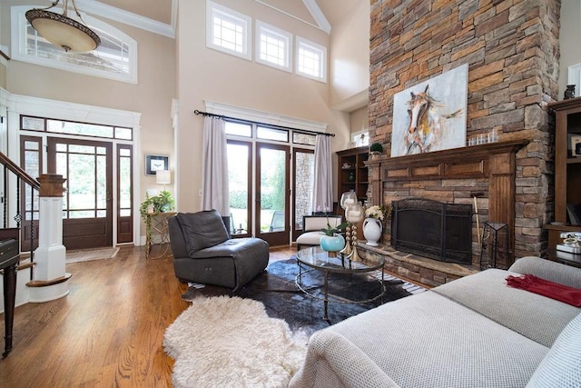 living room with a healthy amount of sunlight, a fireplace, a towering ceiling, and dark hardwood / wood-style flooring