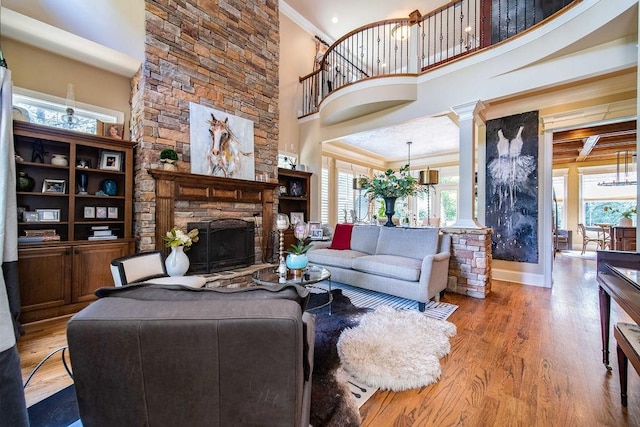 living room with a chandelier, light hardwood / wood-style floors, a towering ceiling, and a fireplace