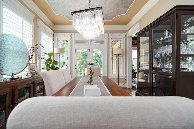 dining area with dark wood-type flooring, ornamental molding, a chandelier, and french doors