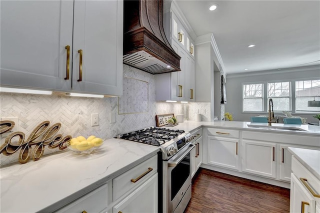 kitchen with gas range, crown molding, premium range hood, white cabinetry, and a sink