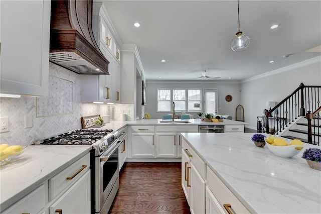 kitchen with premium range hood, a sink, white cabinets, appliances with stainless steel finishes, and crown molding