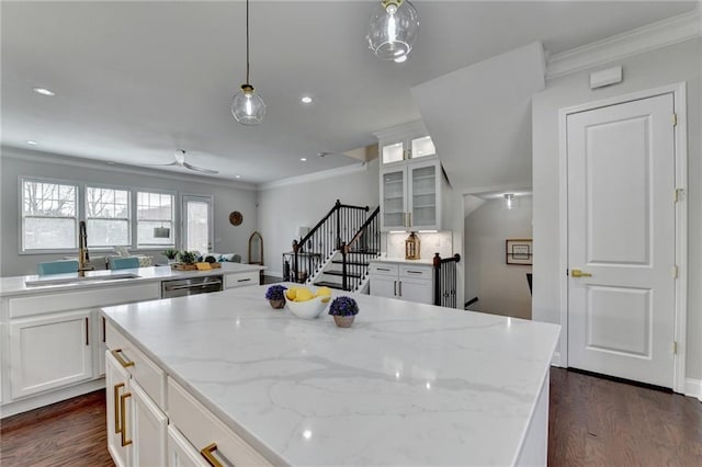 kitchen with glass insert cabinets, a center island, a sink, crown molding, and stainless steel dishwasher