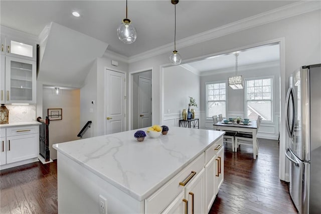 kitchen with ornamental molding, light stone counters, dark wood-type flooring, and freestanding refrigerator