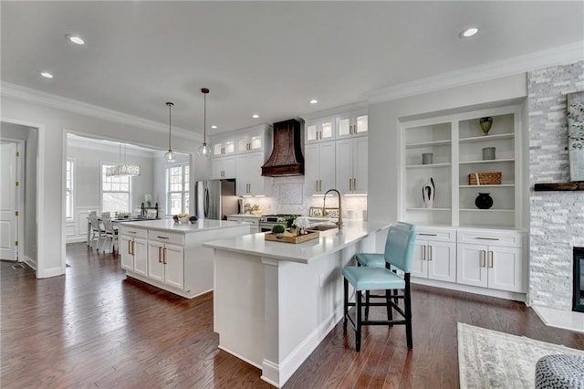 kitchen featuring dark wood finished floors, appliances with stainless steel finishes, a center island, custom exhaust hood, and a sink