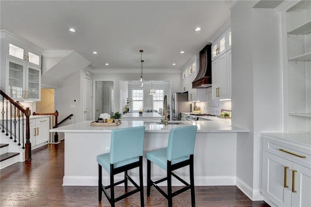 kitchen with dark wood-type flooring, a kitchen breakfast bar, light countertops, ornamental molding, and custom range hood