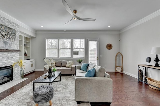 living room with ornamental molding, dark wood finished floors, a stone fireplace, and baseboards