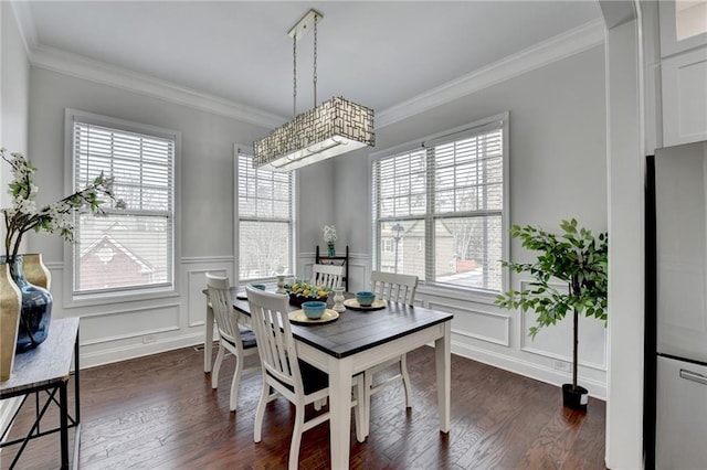 dining area with dark wood-style floors, a decorative wall, wainscoting, and crown molding