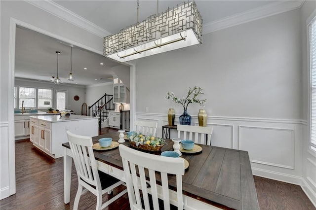 dining room featuring stairs, ornamental molding, dark wood finished floors, and a decorative wall