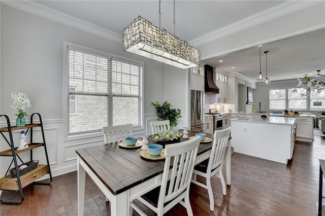 dining room with ornamental molding, dark wood-type flooring, wainscoting, and a decorative wall