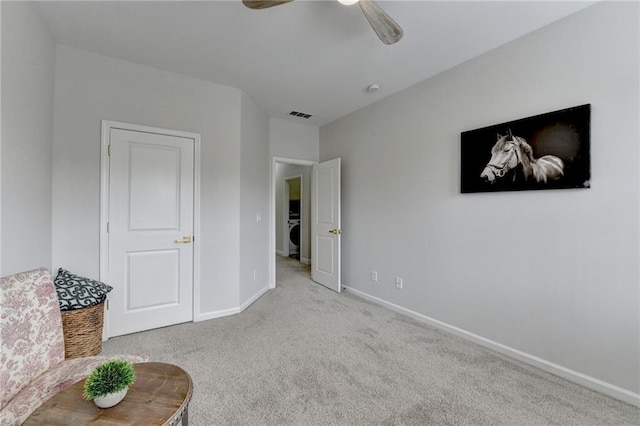 unfurnished room with a ceiling fan, visible vents, baseboards, carpet, and washer / dryer