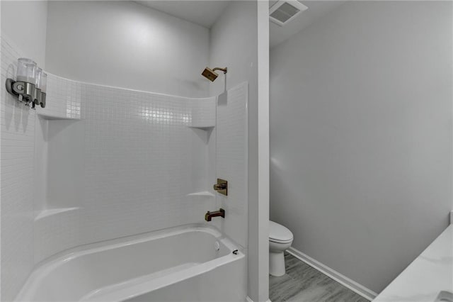 bathroom with baseboards, visible vents, toilet, wood finished floors, and bathtub / shower combination