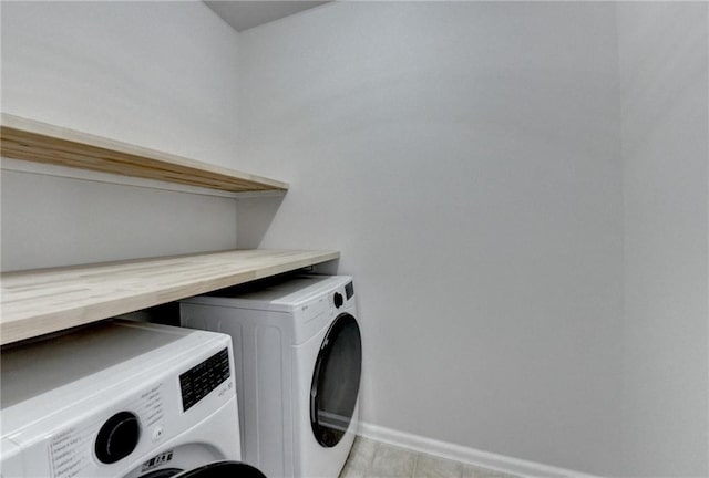 washroom featuring laundry area, baseboards, and washer and clothes dryer