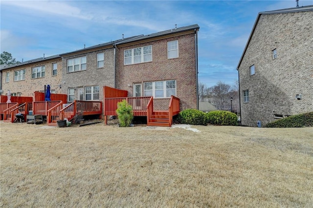 back of house with brick siding, a yard, and a deck