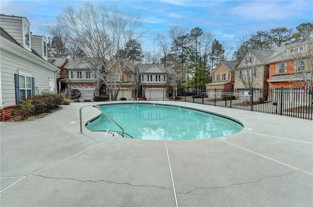 pool with a patio area, a residential view, and fence