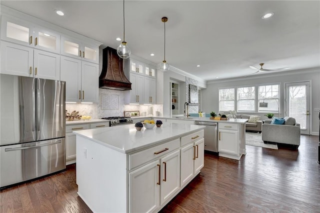 kitchen with stainless steel appliances, light countertops, open floor plan, premium range hood, and a peninsula