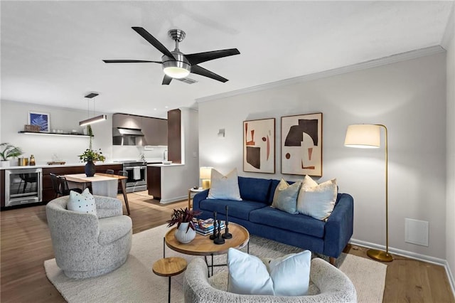 living room featuring crown molding, wine cooler, and light hardwood / wood-style flooring