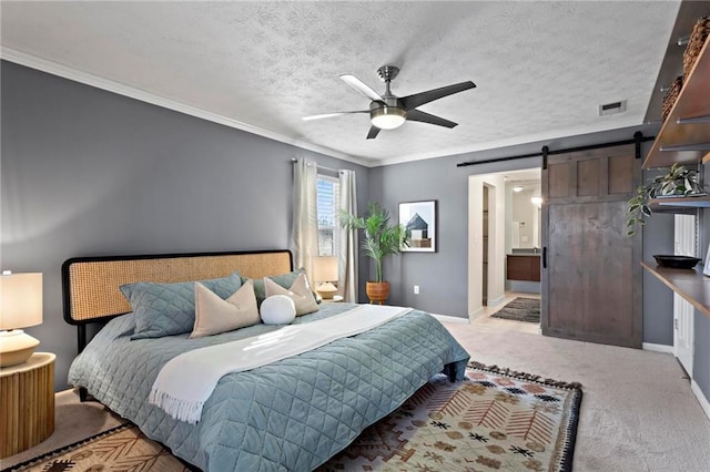 bedroom featuring ensuite bathroom, a textured ceiling, light colored carpet, ceiling fan, and a barn door