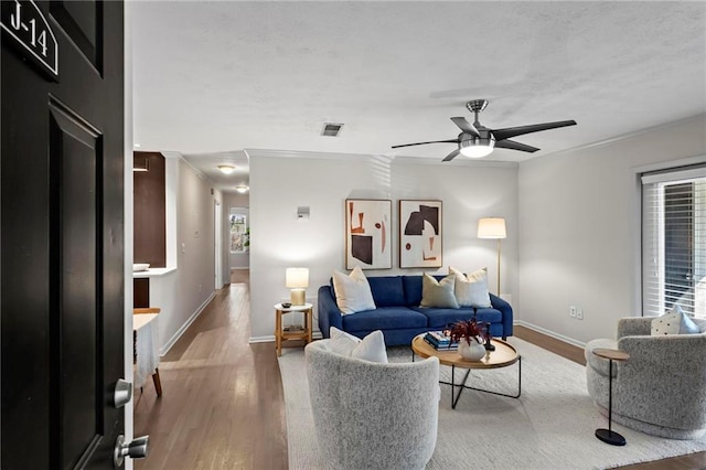 living room with hardwood / wood-style flooring, ceiling fan, and ornamental molding