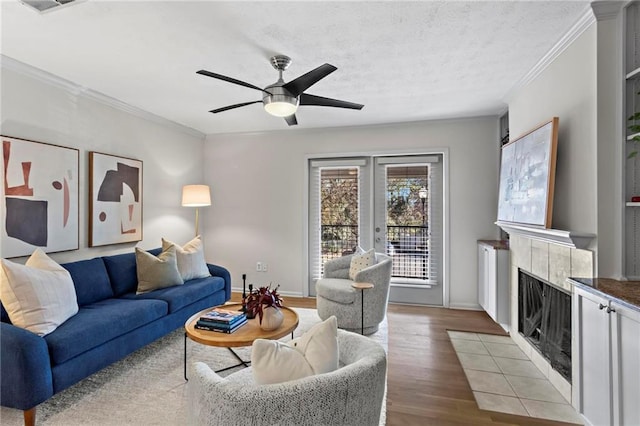 living room featuring crown molding, a fireplace, a wealth of natural light, and light hardwood / wood-style flooring