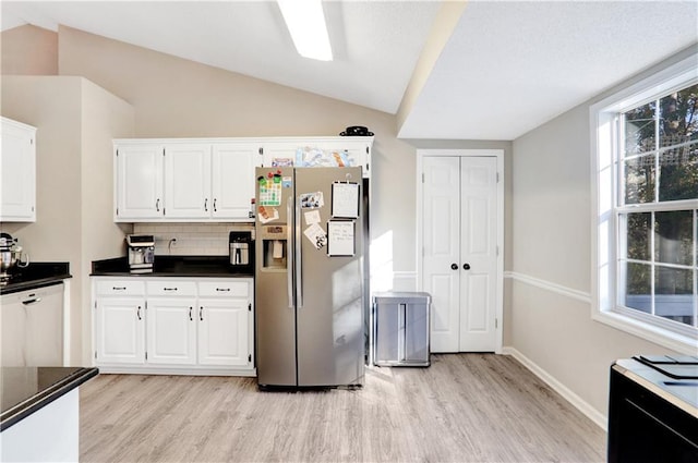 kitchen featuring stainless steel fridge with ice dispenser, white dishwasher, vaulted ceiling, decorative backsplash, and white cabinets