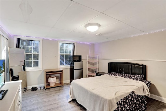 bedroom featuring stainless steel fridge and light wood-type flooring