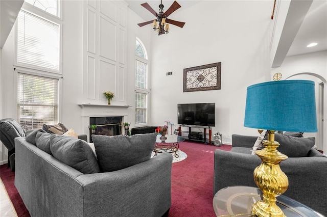 living room featuring carpet, a large fireplace, a high ceiling, and ceiling fan