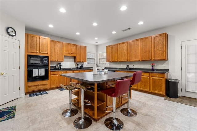 kitchen with black appliances, sink, a kitchen island, and a kitchen breakfast bar