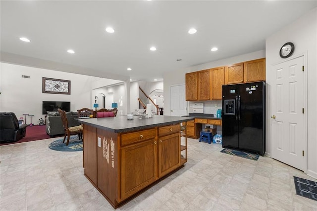 kitchen featuring a kitchen island with sink and black refrigerator with ice dispenser