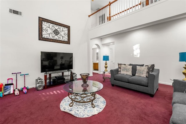 living room featuring a towering ceiling and carpet floors