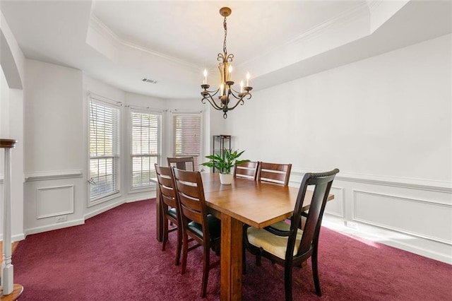 dining space with ornamental molding, a notable chandelier, dark colored carpet, and a tray ceiling