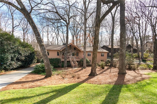 view of front of property featuring stairs, a front lawn, and a wooden deck