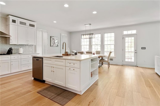 kitchen featuring dishwasher, a kitchen island with sink, white cabinets, sink, and decorative light fixtures